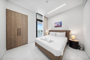 A modern bedroom with a large bed, a wardrobe, a nightstand, and a painting on the wall. - StayShort - Spacious 2-Bedroom Apartment at Skyhills Tower 1 (Arjan)