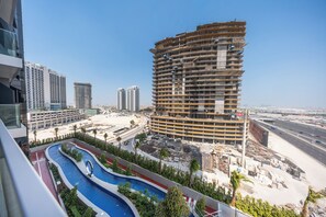 A high-rise building under construction with a swimming pool and a road in the foreground. - StayShort - Spacious 2-Bedroom Apartment at Skyhills Tower 1 (Arjan)
