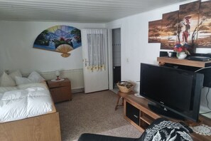 A bedroom with a bed, a TV, a painting, and a door. - Bungalow with 2 bedrooms (Großwoltersdorf)