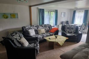 A living room with a sofa, armchairs, a coffee table, and a dining table with chairs. - Bungalow with 2 bedrooms (Großwoltersdorf)