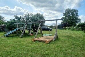 A grassy outdoor area with a swing set and a slide. - Bungalow with 2 bedrooms (Großwoltersdorf)