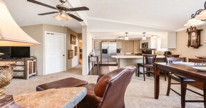 A spacious living area with a dining table, leather chairs, a television, and a ceiling fan. - Corporate Retreat: A Cottage in the City (Auburn Hills)