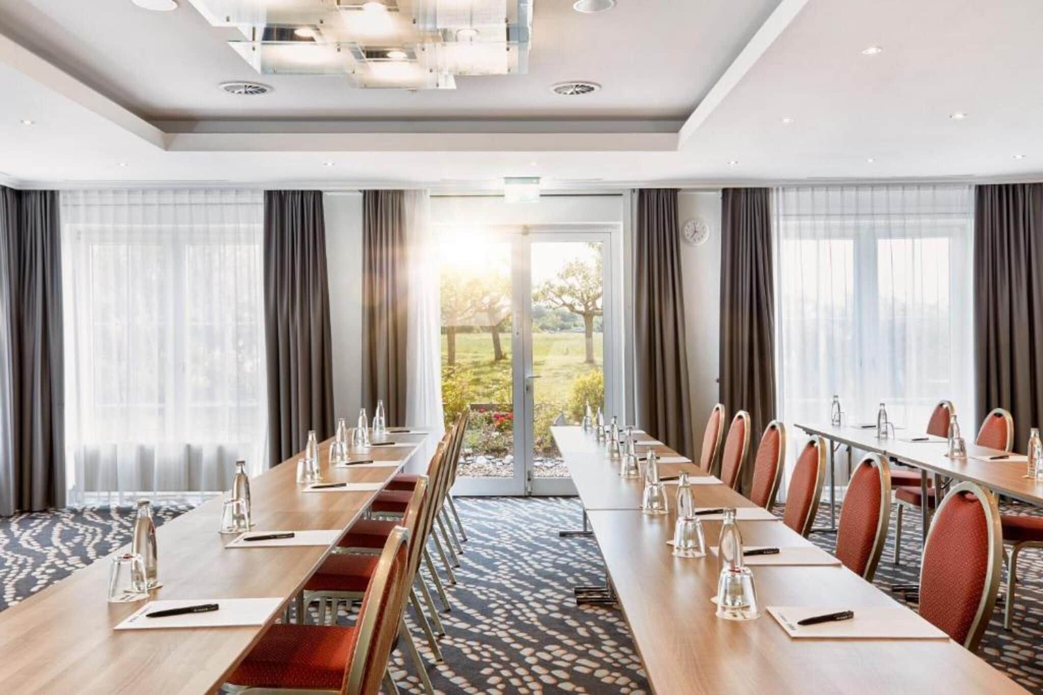 A conference room with a long table, chairs, and a view of the outdoors.