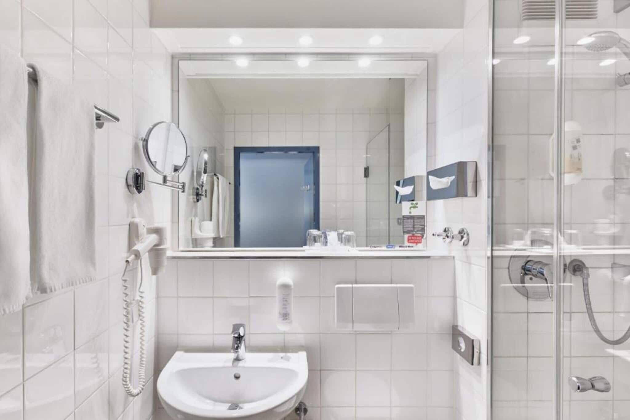 Ein modernes Badezimmer mit Waschbecken, Spiegel und Dusche.