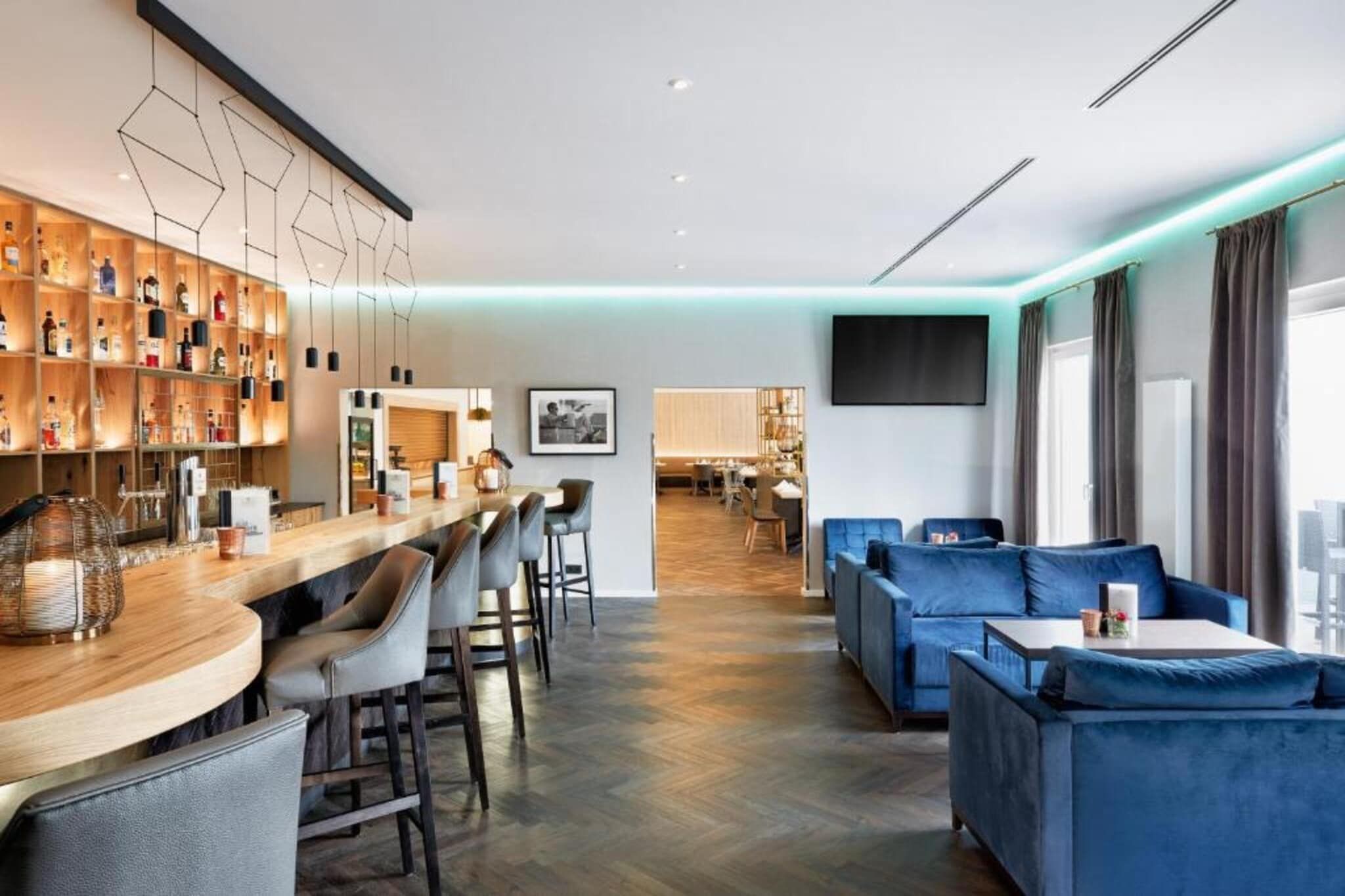 A modern hotel lobby with a bar area, seating, and a television.