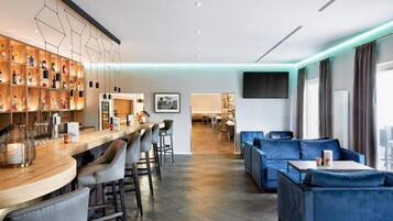 A modern hotel lobby with a bar area, seating, and a television.