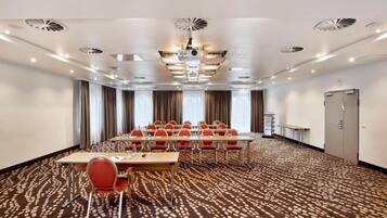 A conference room with a long table, red chairs, and a patterned carpet.