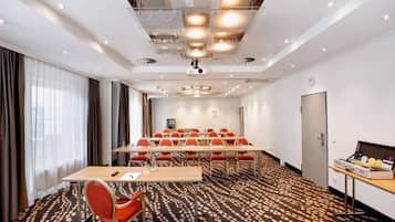 Uma sala de conferências com uma mesa comprida, várias cadeiras, um projetor e um relógio na parede.