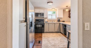 A compact kitchen with a refrigerator, oven, microwave, and sink. - Corporate Retreat Cottage in the city (Auburn Hills)