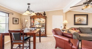 A dining area with a wooden table and chairs, a chandelier, and a mirror above the table. - Corporate Retreat Cottage in the city (Auburn Hills)