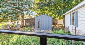 A wooden deck with a metal railing, a small shed, and a house with shutters. - Corporate Retreat Cottage in the city (Auburn Hills)
