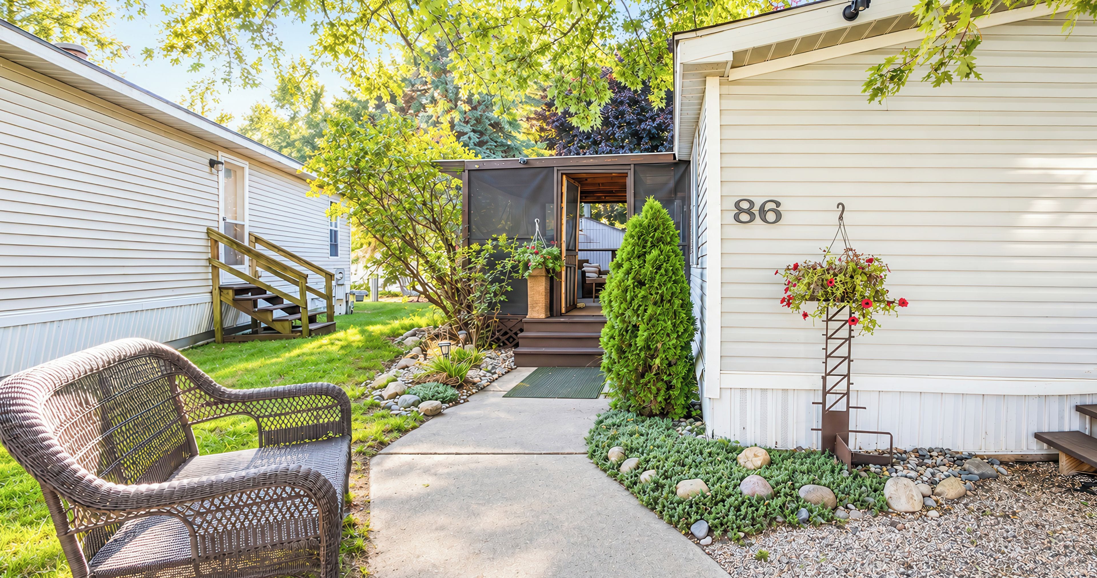 A residential property with a pathway leading to a front door, a porch with a chair, and a mailbox.
