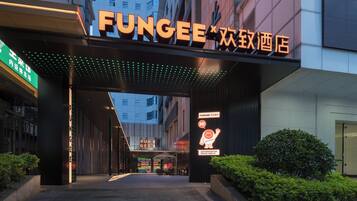 A hotel entrance with a prominent sign reading 'FUNGEE' and a neon sign indicating a restaurant.