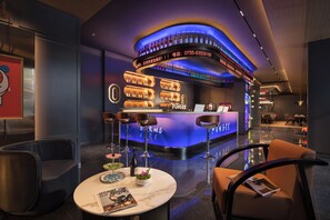 Zona de bar moderna con una barra curva, diversas opciones de asientos y una variedad de botellas exhibidas.