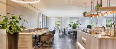 Un moderno vestíbulo de hotel con una larga recepción, zona de estar y un bar.
