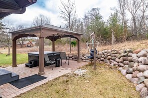 Eine überdachte Grillanlage auf einer Terrasse, eine Steinmauer und ein Hinweisschild.