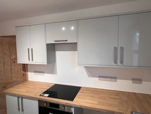 Eine moderne Küche mit weißen Schränken, einer schwarzen Induktionskochplatte und Holz Arbeitsplatten.