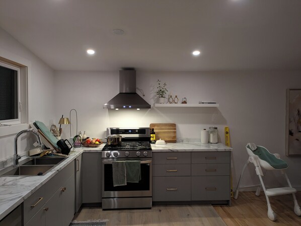 A modern kitchen with a built-in oven, a gas stove, a sink, and a countertop with various items.