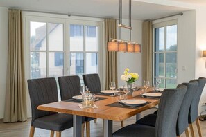 A dining area with a long table, multiple chairs, and a hanging light fixture. - Holiday home Seestern (Kramerhof OT Parow)