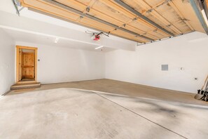 A spacious, unfinished room with a concrete floor, a wooden door, and a metal ceiling structure. - Shaquinaw - Mountain views, Hot tub & Game Room! (South Lake Tahoe)