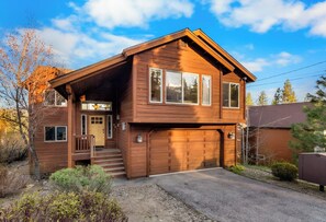 Une maison en bois à deux étages, dotée d’un porche à l’avant, d’un garage et d’une allée.