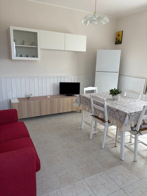 A modern kitchen with a dining area, a television, and a red couch. - Holiday house 'Rita's Home' (Paringianu)