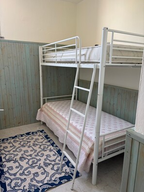 A bunk bed with a ladder, a patterned rug, and wooden panel walls. - Holiday house 'Rita's Home' (Paringianu)
