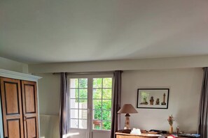 A room with a large window, a wooden wardrobe, a desk with a lamp, and a framed picture on the wall. - in Brittany || Plounéour-Brignogan-Plag (Plounéour-Brignogan-Plag)