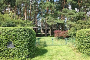 A well-maintained garden with a hedge, a metal gate, and tall trees in the background. - Holiday home "THREE" at the Gr. Mochowsee (Schwielochsee OT Groß Liebitz)