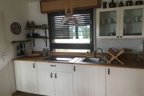 Eine Küche mit weißen Schränken, einem Fenster mit schwarzem Rahmen und einer Holzarbeitsplatte.