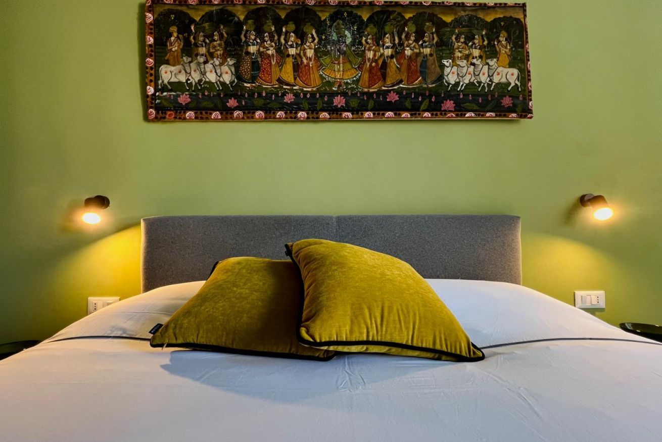 Ein Bett mit zwei Kissen, einem Kopfteil und einem Wandbild.