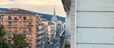 Rua urbana com edifícios altos, uma torre imponente e céu claro.