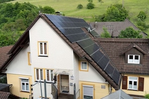 Ein zweistöckiges Haus mit geneigtem Dach, einer sichtbaren Treppe und einer kleinen Veranda.