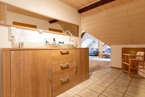Ein Holzkabinent mit Schubladen und einem Spiegel darüber in einem Raum mit geneigter Decke und Blick auf einen Wohnbereich.