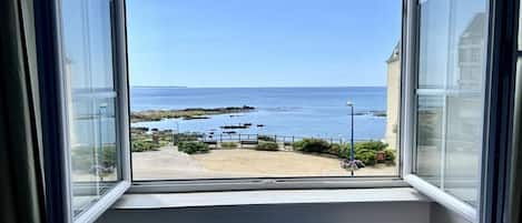 A window with a view of a beach and the sea.
