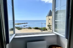 A room with a view of the sea, a building across the water, and a window sill. - Holiday home in Clohars Carnoët with parking (Clohars Carnoët)