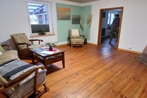Ein Wohnzimmer mit Holzboden, einer Couch, einem Sessel und einem Couchtisch.