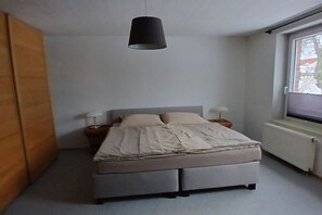 Ein Schlafzimmer mit einem Bett, Nachttischlampen, einem Fenster und einer Heizung.