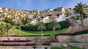 Un quartiere residenziale su una collina con diversi edifici a più piani, vegetazione lussureggiante e un muro di sostegno in pietra.