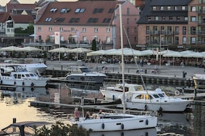 A marina with boats docked, a café with outdoor seating, and buildings in the background. - Holiday apartment with 1 bedroom (Waren \/ Müritz)