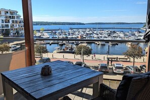 A balcony with a view of a marina and boats, a table with a decorative item, and a cityscape in the background. - Holiday apartment with 1 bedroom (Waren \/ Müritz)