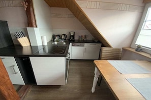 A compact kitchen with a stove, sink, and white cabinets. - Holiday apartment with 1 bedroom (Waren \/ Müritz)