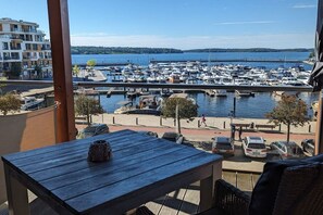 Un balcó amb vista a una marina, una taula i una banca.