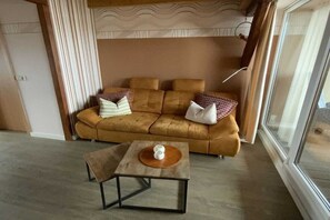 A modern living room with a sofa, a coffee table, and a window. - Holiday apartment with 1 bedroom (Waren \/ Müritz)