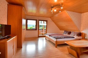 A bedroom with a bed, a TV, and a wooden ceiling. - Holiday apartment with 2 bedrooms (Oppenau)