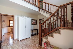 Un pasillo amplio con una escalera de madera, un armario blanco y un comedor.
