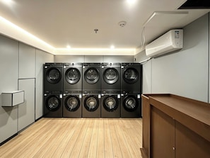 Una sala de bugaderia amb diverses rentadores, un terra de fusta i una banca integrada.