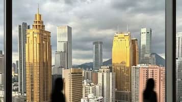 A view of a cityscape through large windows, with buildings of various heights and designs.