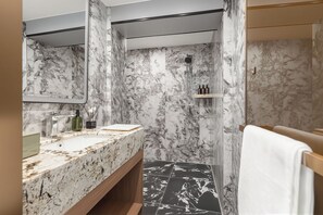 Een badkamer met een marmeren wastafel, een douche en een handdoekrek.