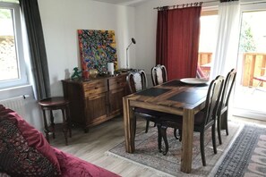 Ein Essbereich mit Holztisch und Stühlen, einem roten Vorhang und einem farbenfrohen, abstrakten Gemälde an der Wand.